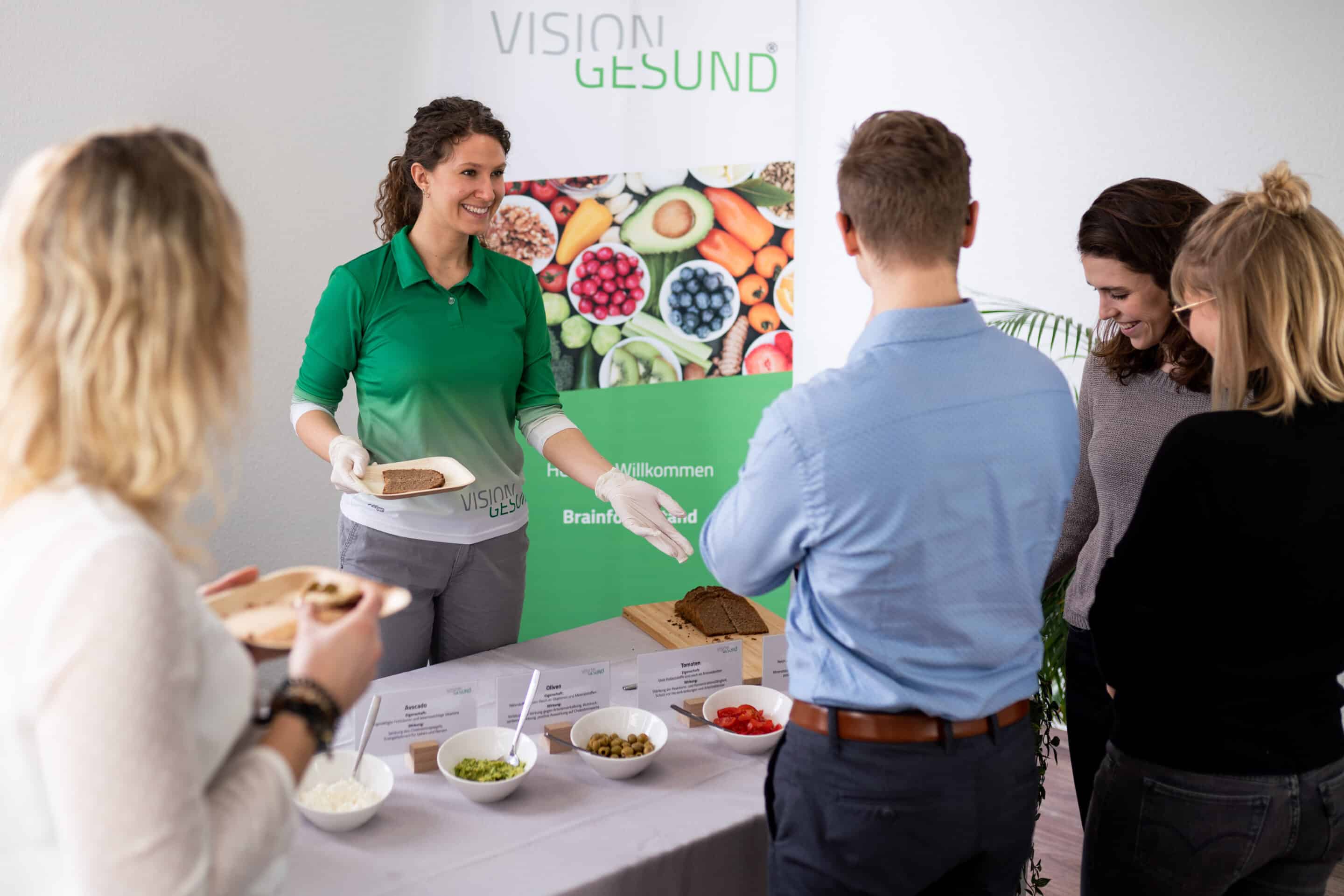 Eine Fachkraft erklärt einer Gruppe gesundheitsförderliche Ernährung anhand verschiedener Lebensmittel im Rahmen des BGF‑Programms.