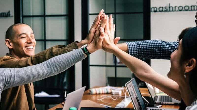 Vier Personen geben sich lachend ein High-Five und klatschen sich ab